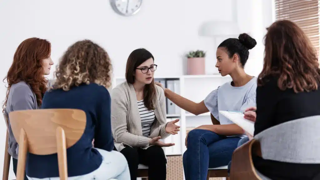 Group of women smiling and talking together during a supportive mental health therapy session.