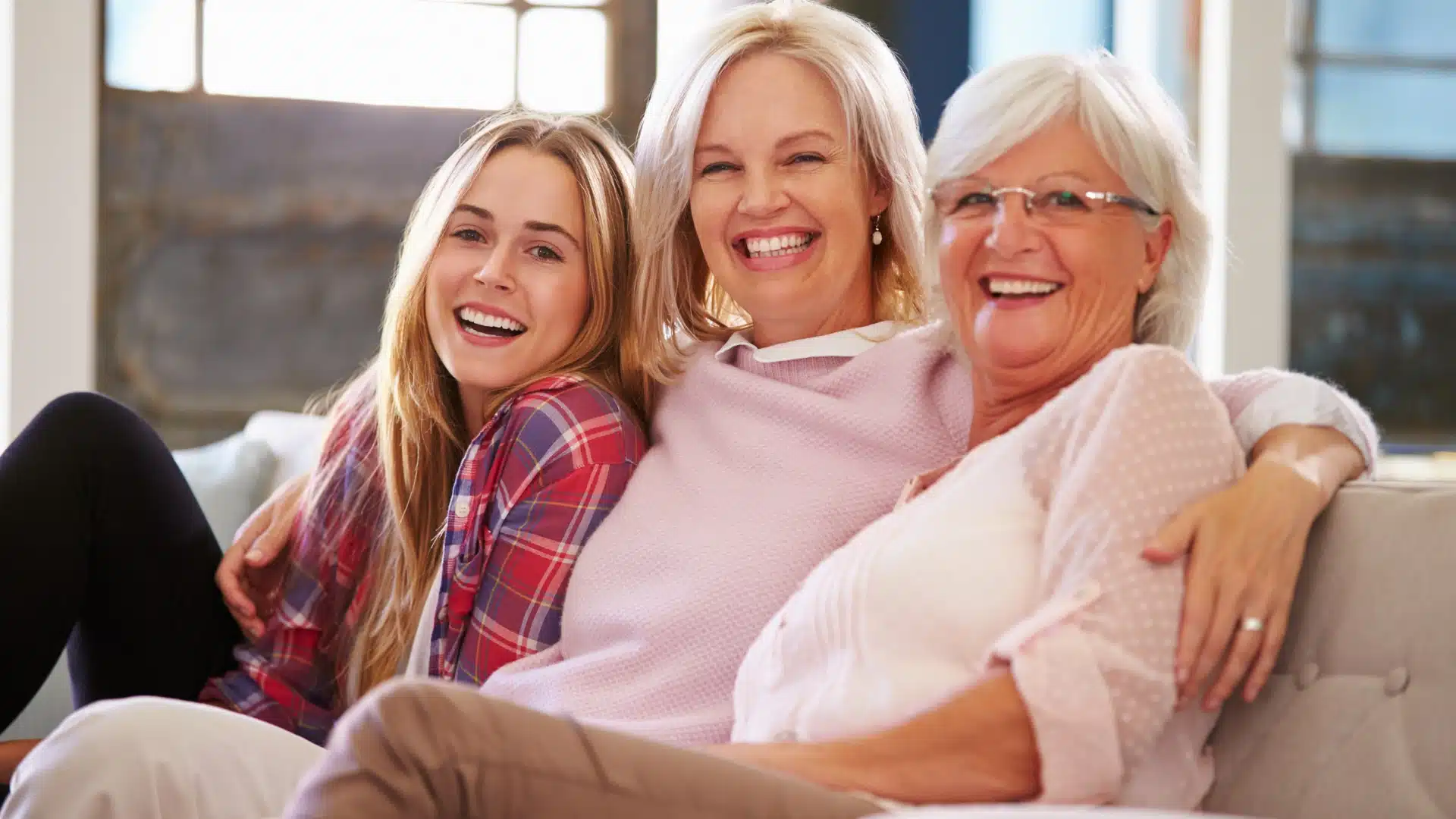 Three generations of women smiling and sitting together on a couch