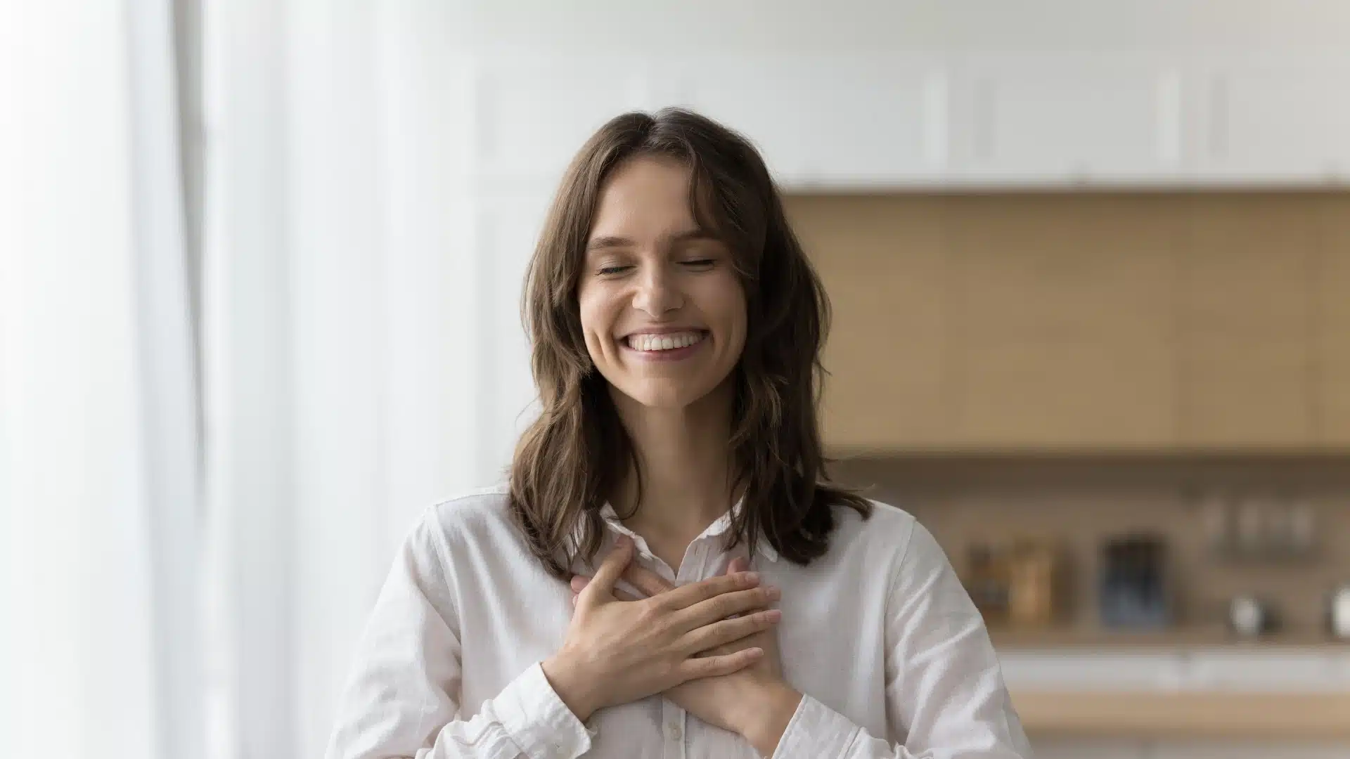 Smiling woman with eyes closed and hands on chest, symbolizing emotional healing and inner peace during trauma recovery.