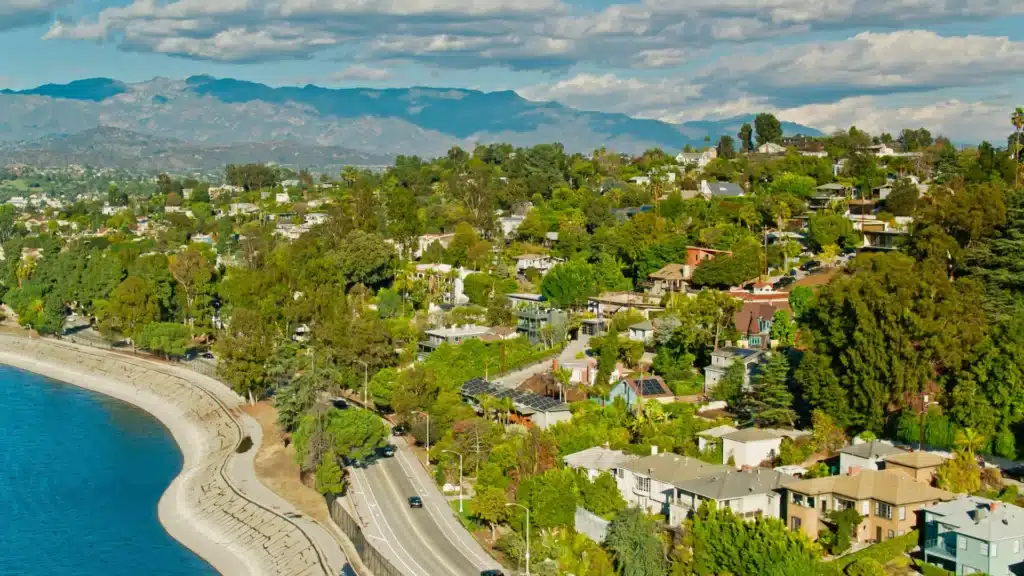 A scenic view of Mission Viejo, California, showing rolling hills, peaceful neighborhoods, and the calm waters of Lake Mission Viejo surrounded by lush greenery under a clear sky.