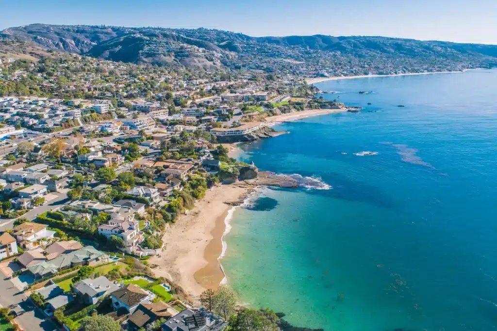 Aerial view of Laguna Beach coastline with turquoise water, sandy coves, and homes along the hills.