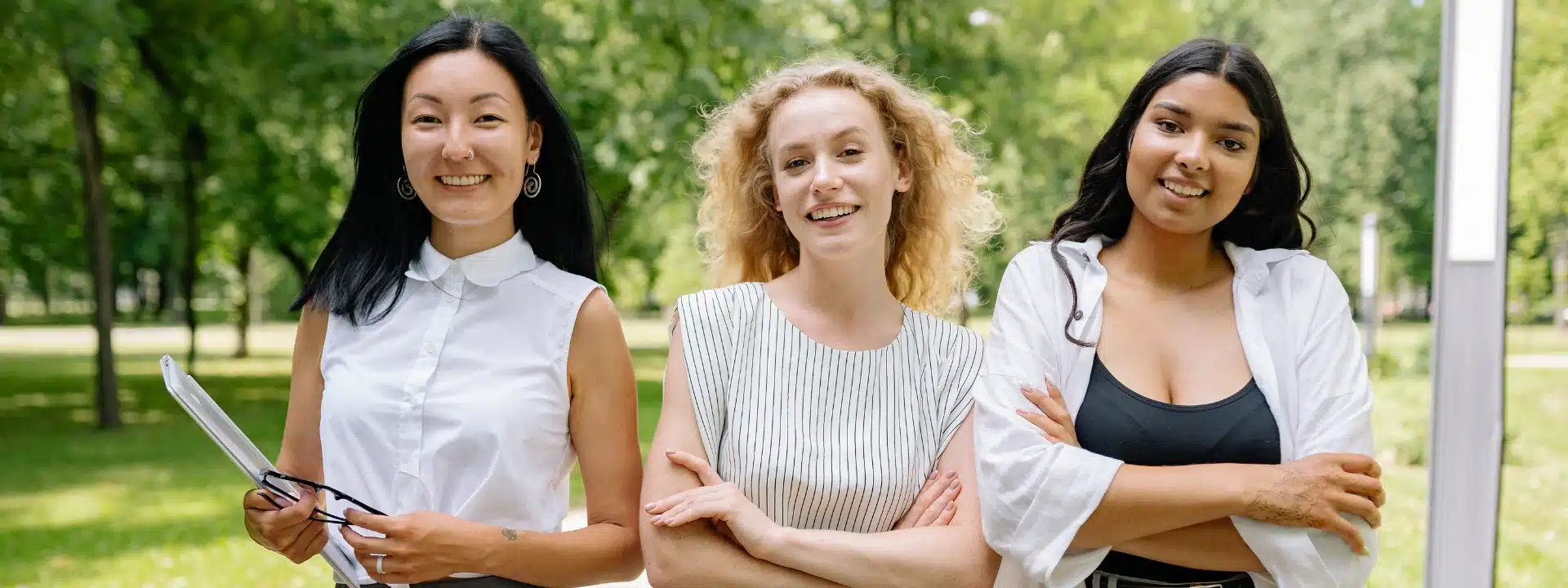Three women smiling outdoors together.