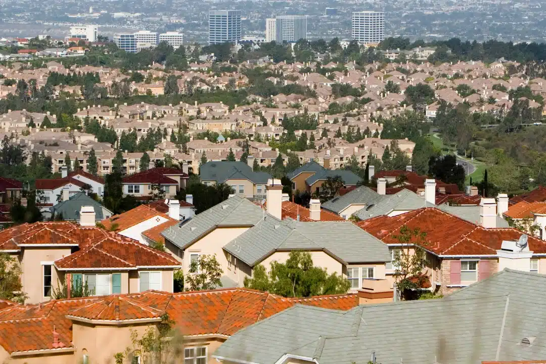 Dense suburban neighborhood with tiled rooftops and office buildings in the distance.